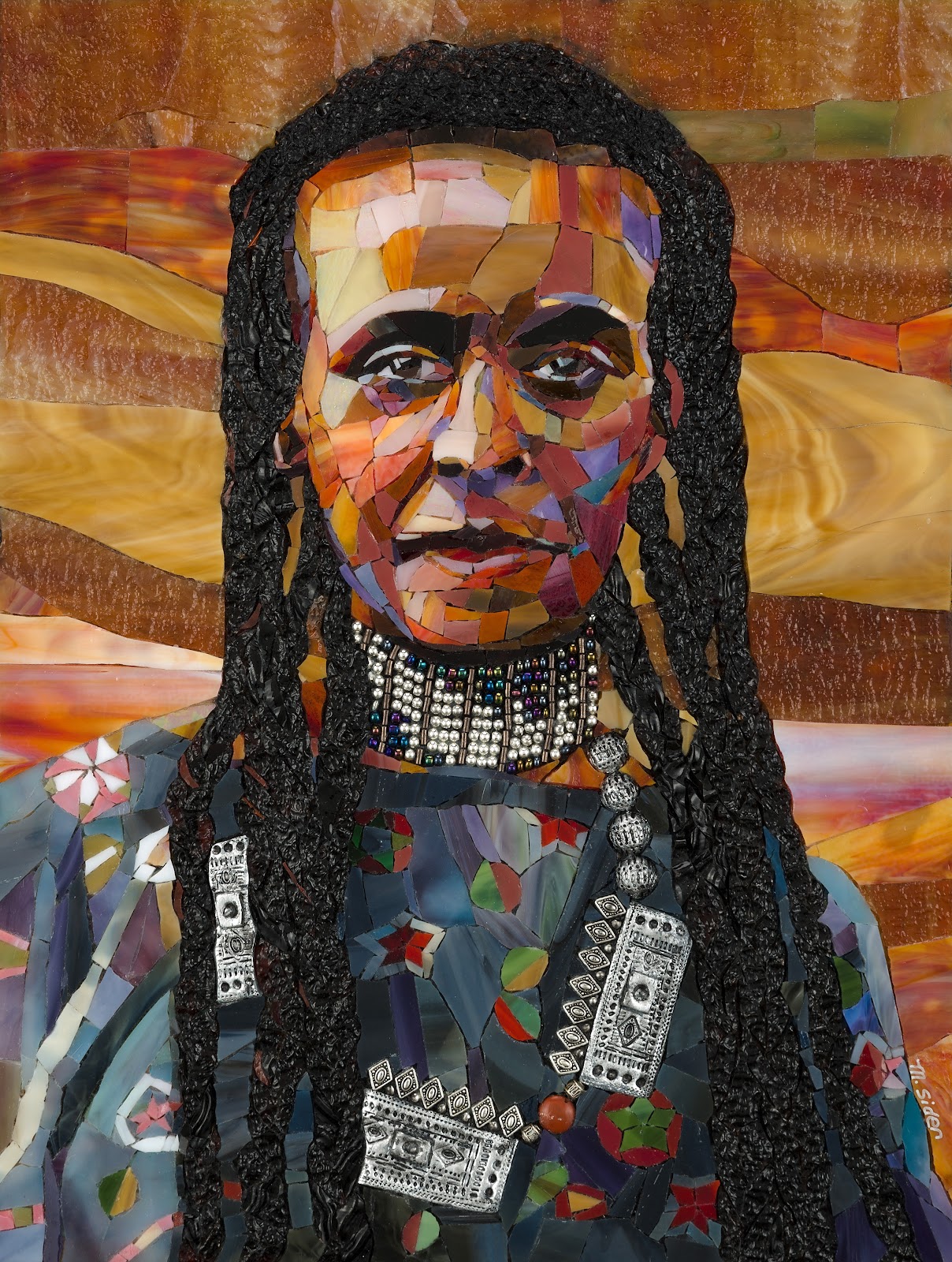 Glass mosaic portrait of a person with long, thick braids; the face area is covered by a rectangular blur. The figure wears layered beaded and silver-toned jewelry over a multicolored, patchwork-like glass garment, set against a background of warm, wavy bands of amber, gold, and brown glass pieces.