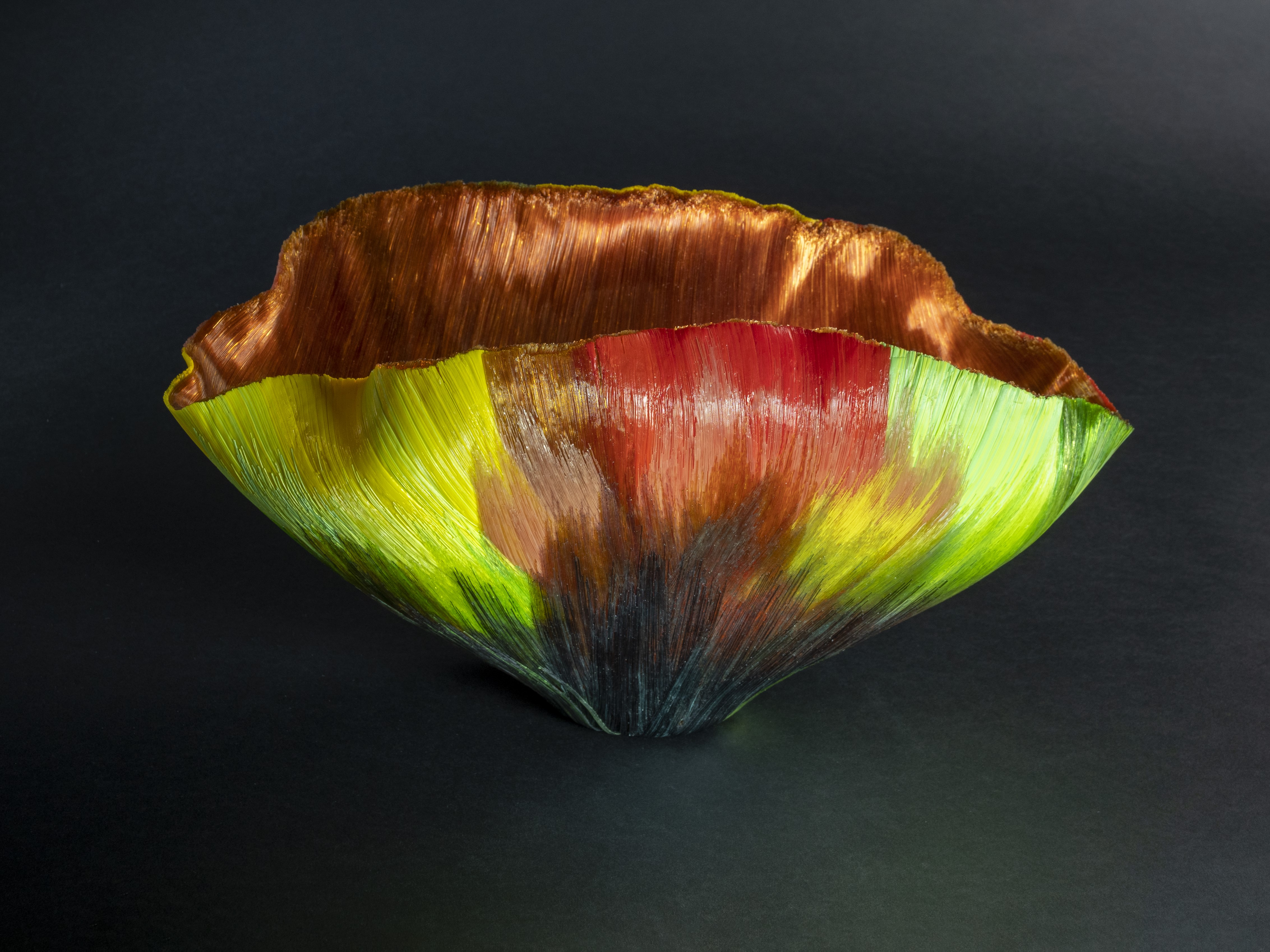 A colorful, textured bowl with an organic, wavy rim. The outside of the bowl features vibrant shades of green, yellow, red, and black, while the inside has a metallic copper finish.