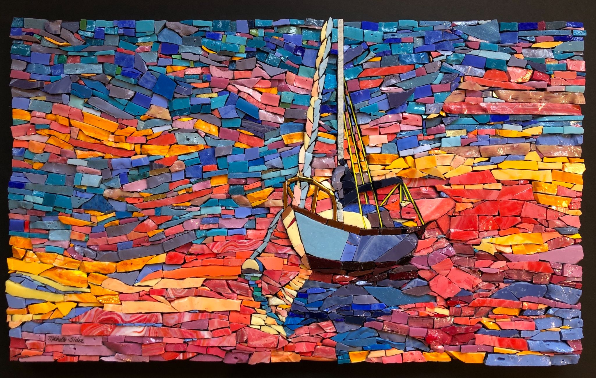 Glass mosaic of a small sailboat with pale sails and a blue-and-white hull floating on vivid red, orange, purple, and blue water beneath a matching multicolored sky.