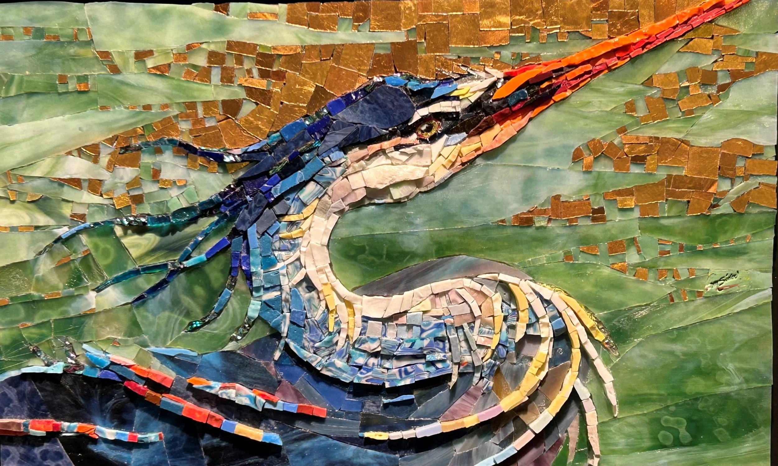 A colorful mosaic artwork of a long-beaked bird in profile, perched against swirling green water and a gold-tiled sky. The bird’s head and body are formed from layered blue, white, and yellow fragments, with an orange beak and flowing, textured feathers that create a sense of movement.
